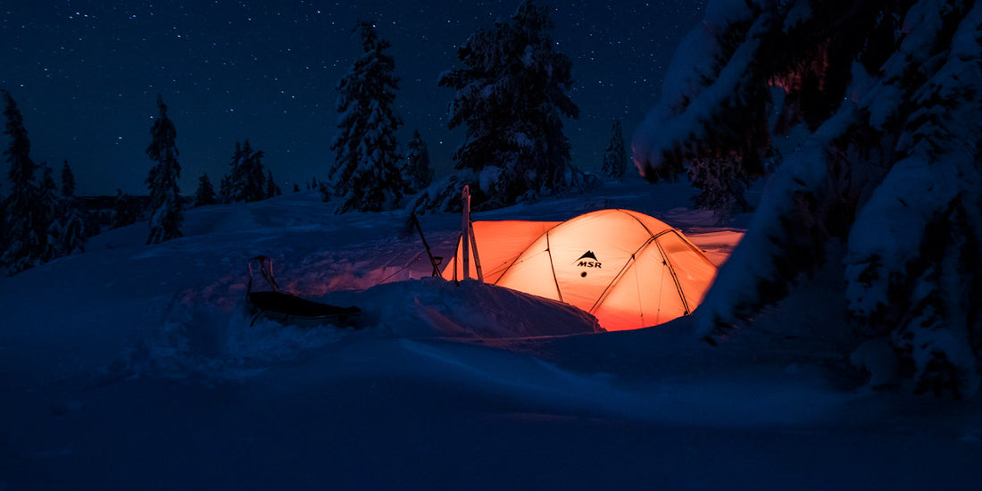 MSR tent glowing at night surrounded by snow